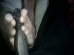 My wife uses her incredibly talented feet to massage my big, ebony ramrod.